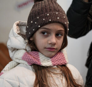 En ukrainsk flicka ser allvarlig ut, iklädd vinterjackam halsduk och mössa.