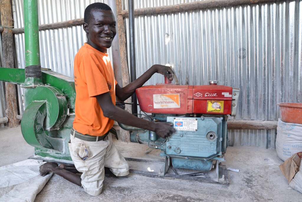 Alex, en ung man med funktionsnedsättning, mekar med en motor och ler mot kameran.