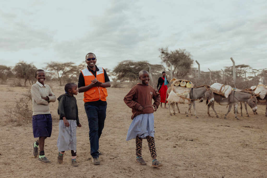 En World Vision medarbetare promenerar leende tillsammans med tre barn.