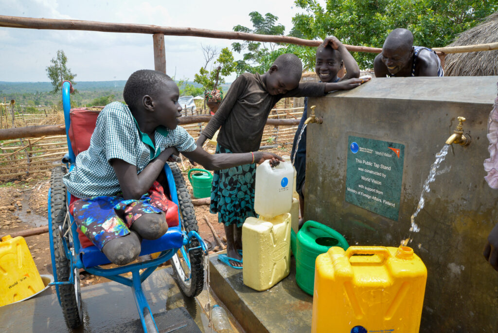 Beatrice, en ung rullstolsbunden flicka på ett flyktingläger i Uganda, fyller en vattentank vid en rullstolsanpassad vattenstation.