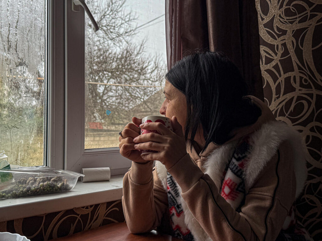 Ukrainska Maryna sitter med en kopp varm dricka i händerna och tittar ut genom fönstret.