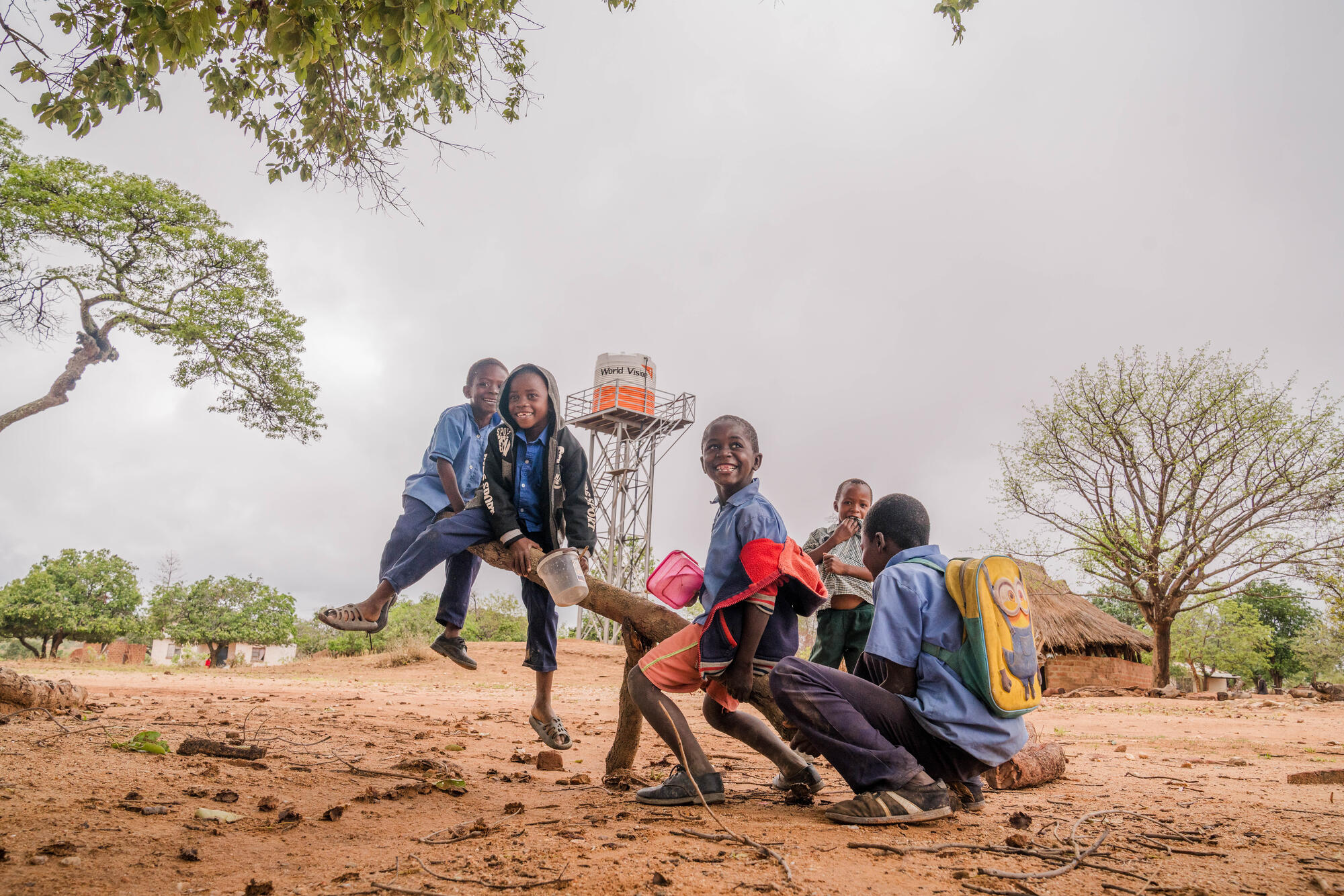 Barn i Zambia gungar tillsammans. I bakgrunden syns ett vattentorn med World Visions logo.